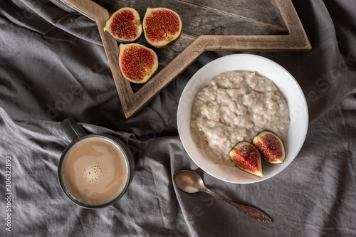 Healthy breakfast in bed. Coffee, porridge with figs, on a rustic wooden board. Clean food, alkaline diet, 
