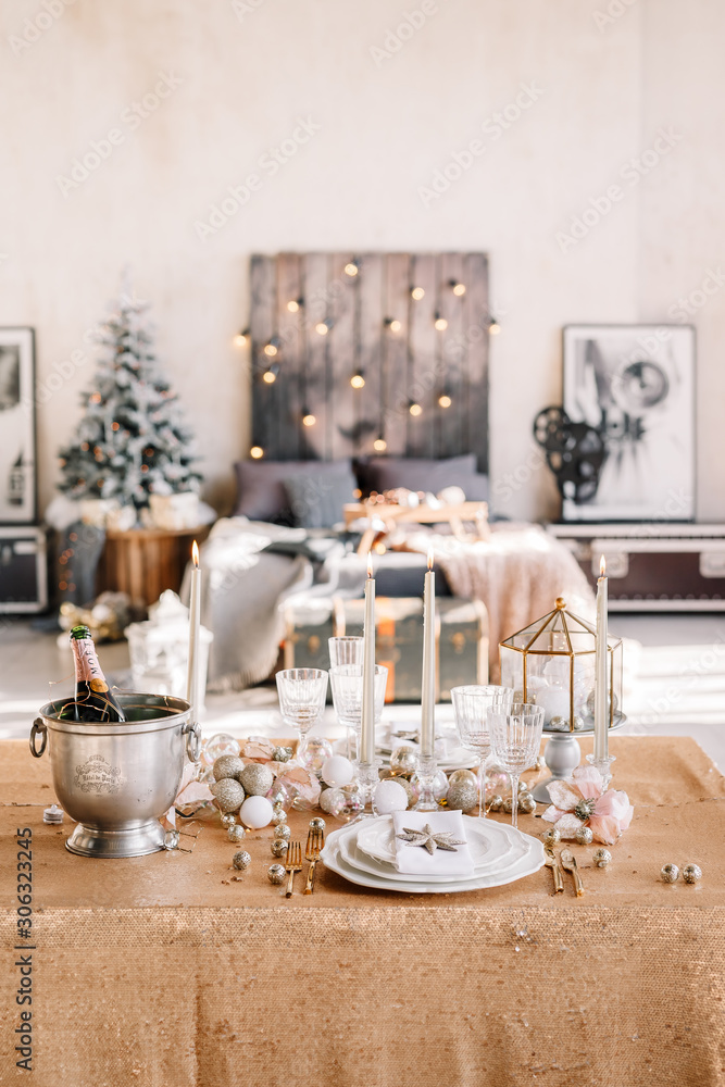 New Year 2020. New Year mood. Table with a gold tablecloth, decorated with candles and tableware for celebration. Festive still life by candlelight. Close-up.