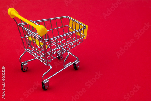 Yellow shopping cart or trolley on red background with copy space
