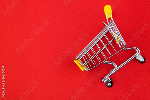 Yellow shopping cart or trolley on red background with copy space
