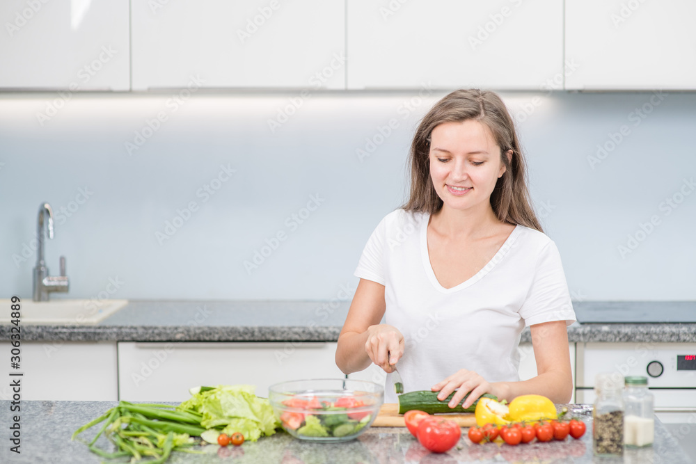 Smiling young woman cooking in the kitchen at home. Empty space for text