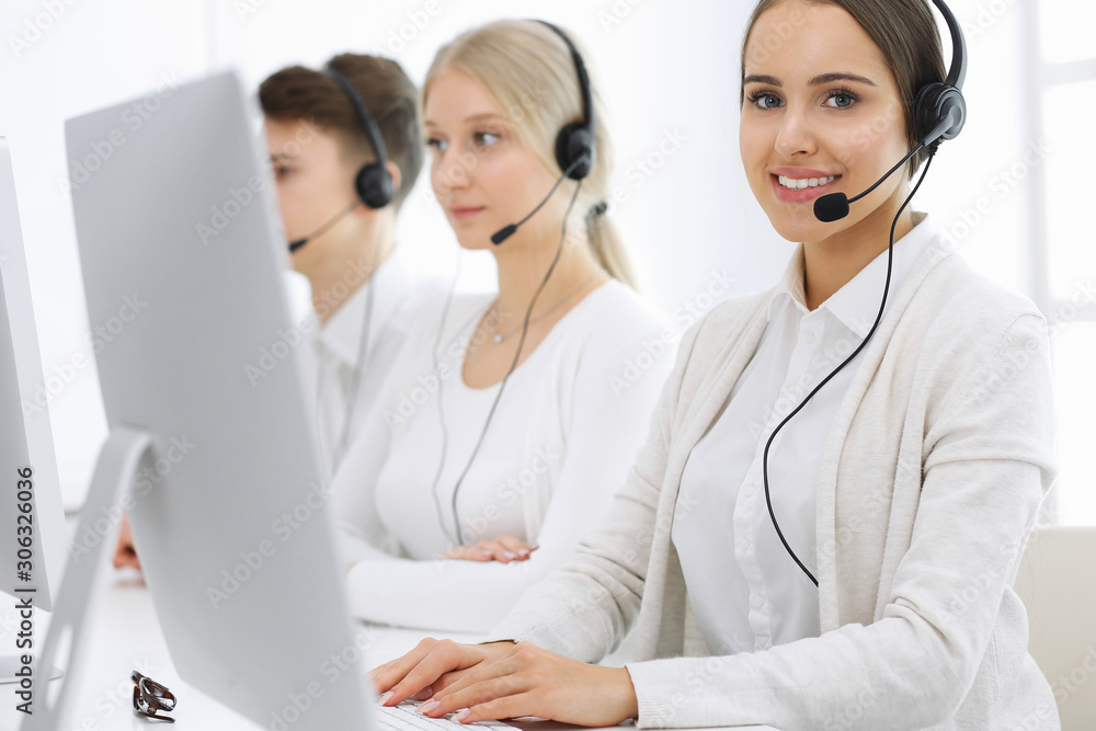 Call center. Group of operators at work. Focus on beautiful woman receptionist in headset at customer service white colored office. Business concept Call center. Group of operators at work. Focus on beautiful woman receptionist in headset at customer service white colored office. Business concept