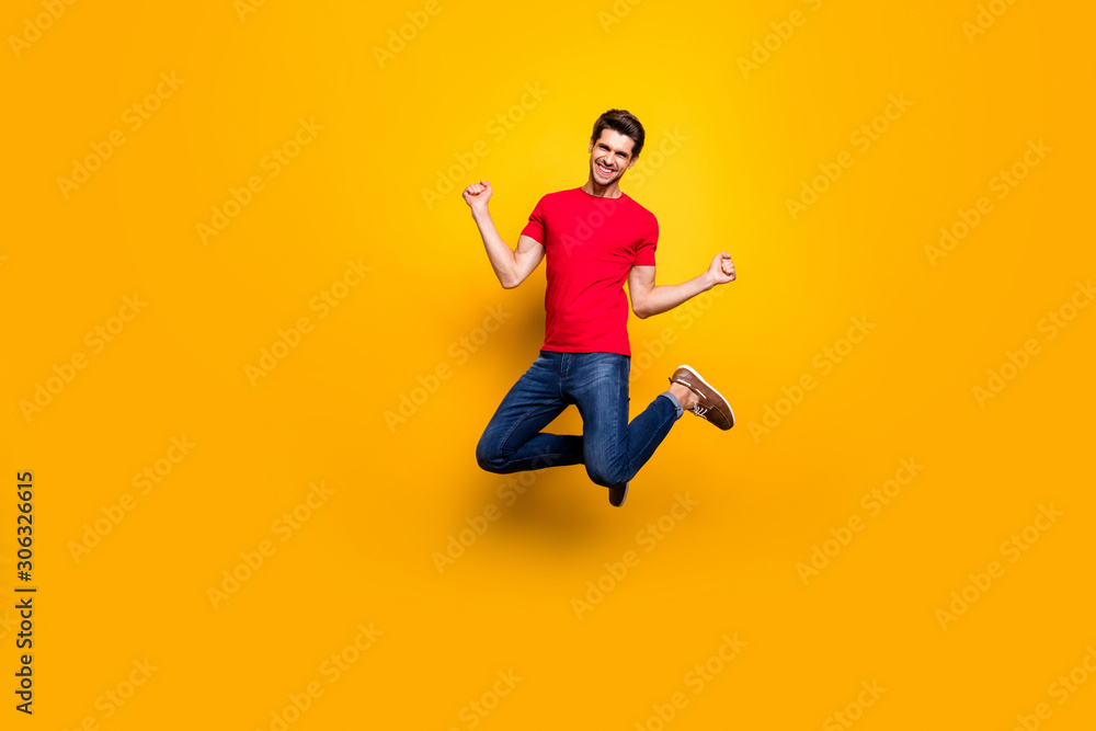 Full size photo of cheerful content guy jump win lottery raise fists wear casual style clothes isolated over yellow color background