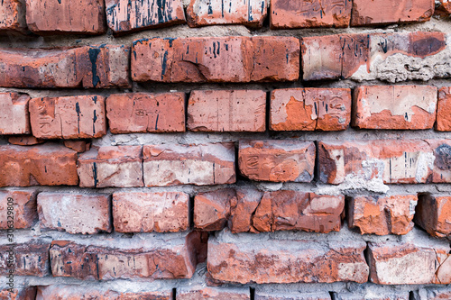 The background is made of red bricks with a wavy relief  cracks  holes and ditches. Building material for decoration and decor in the style of a loft.