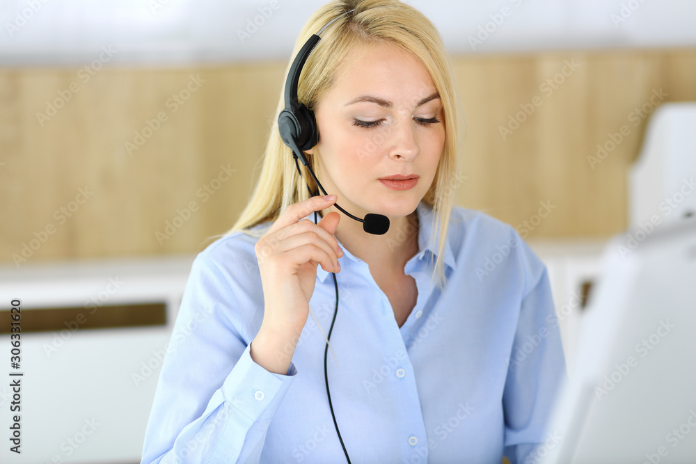 Call center. Blonde business woman sitting in headset at customer service office. Concept of telesales business or home office occupation Call center. Blonde business woman sitting in headset at customer service office. Concept of telesales business or home office occupation