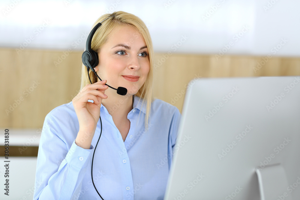 Call center. Blonde business woman sitting in headset at customer service office. Concept of telesales business or home office occupation Call center. Blonde business woman sitting in headset at customer service office. Concept of telesales business or home office occupation