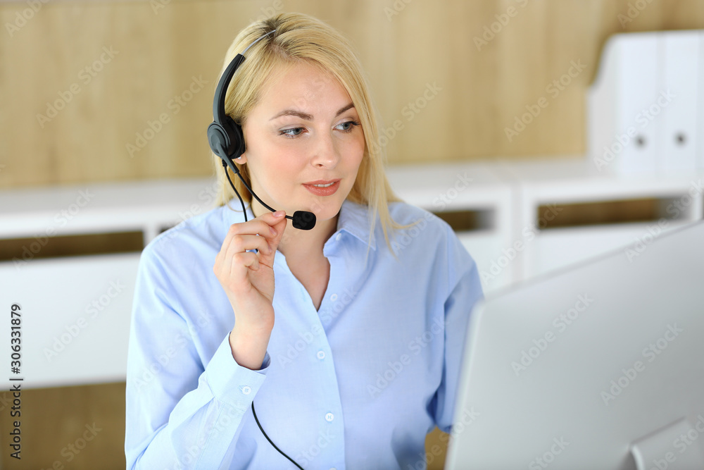 Call center. Blonde business woman sitting in headset at customer service office. Concept of telesales business or home office occupation Call center. Blonde business woman sitting in headset at customer service office. Concept of telesales business or home office occupation