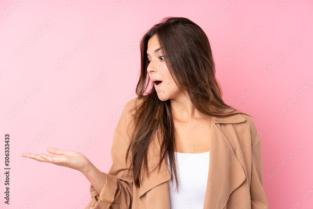 Teenager Brazilian girl over isolated pink background holding copyspace imaginary on the palm Teenager Brazilian girl over isolated pink background holding copyspace imaginary on the palm