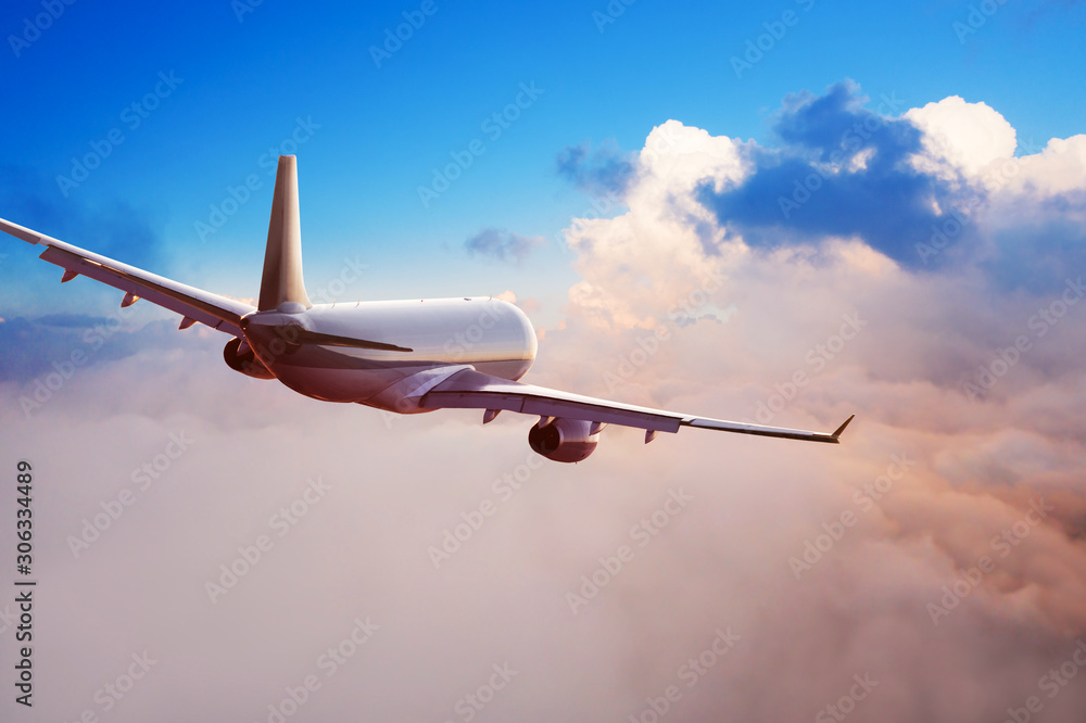 Passengers commercial airplane flying above clouds in sunset light. Concept of fast travel, holidays and business.