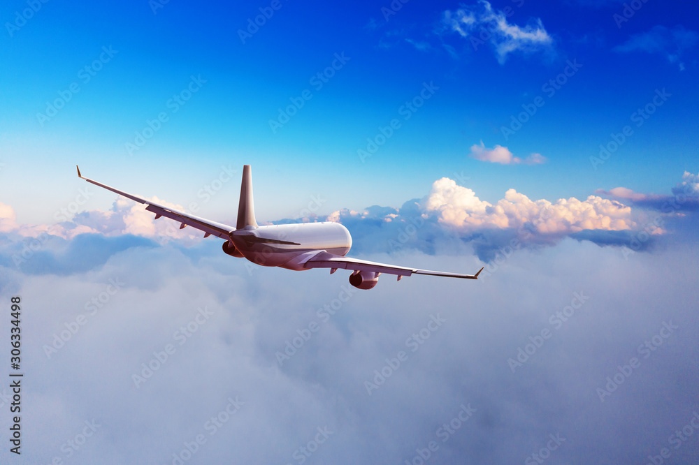 Obraz premium Passengers commercial airplane flying above clouds in sunset light. Concept of fast travel, holidays and business.