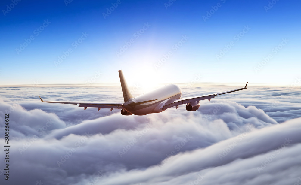 Obraz premium Passengers commercial airplane flying above clouds in sunset light. Concept of fast travel, holidays and business.