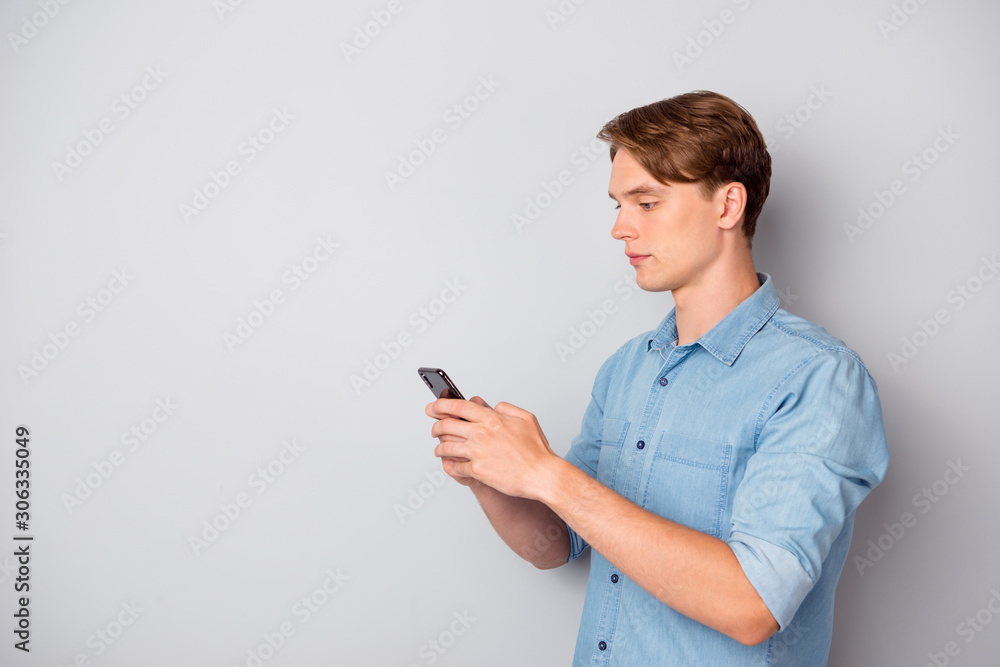 Turned photo of concentrated worker guy use smartphone chatting with colleagues clients on social media text type sms wear good looking outfit isolated over grey color background Turned photo of concentrated worker guy use smartphone chatting with colleagues clients on social media text type sms wear good looking outfit isolated over grey color background