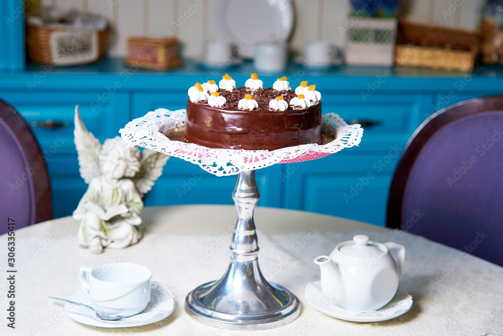 Chocolate cake on a table with a cup and a teapot.