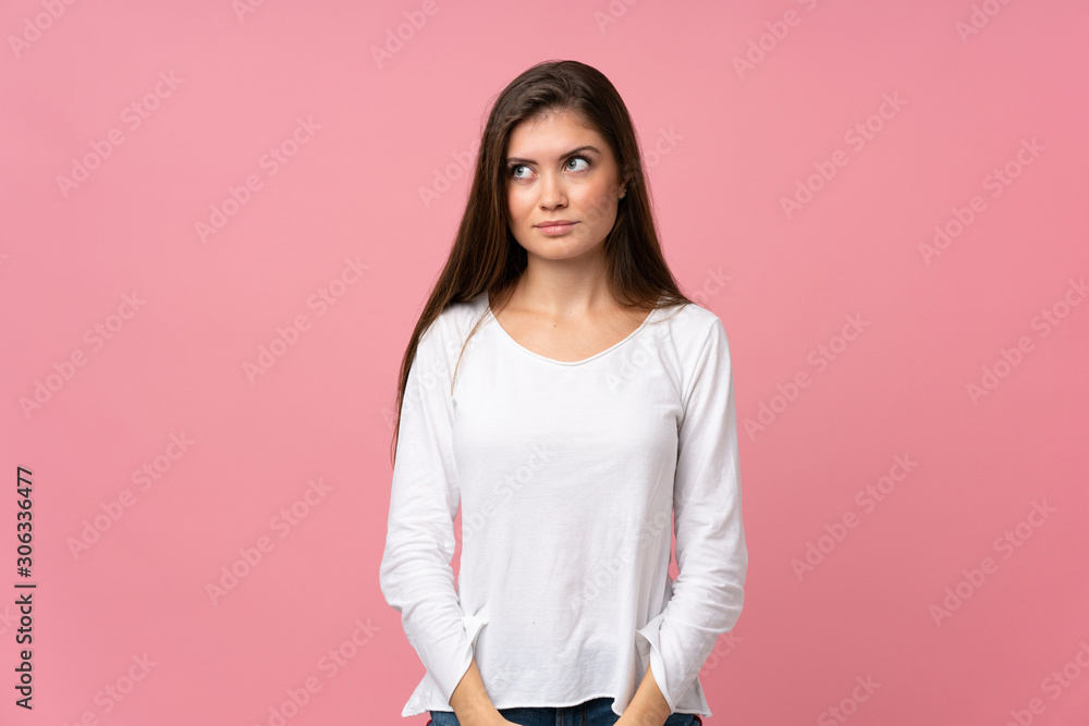 Young woman over isolated pink background making doubts gesture looking side Young woman over isolated pink background making doubts gesture looking side
