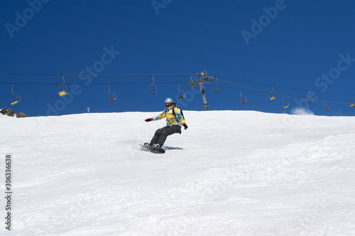 Snowboarder descends on snowy ski slope at winter