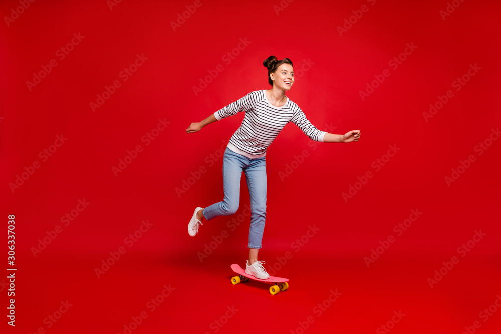 Full length profile side photo of positive cheerful girl ride have autumn free time ride her skateboard wear white outfit sneakers isolated over red color background Full length profile side photo of positive cheerful girl ride have autumn free time ride her skateboard wear white outfit sneakers isolated over red color background