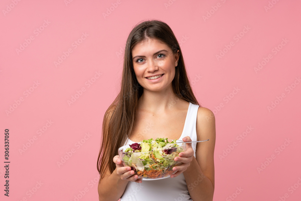 Young woman with salad over isolated pink wall Young woman with salad over isolated pink wall