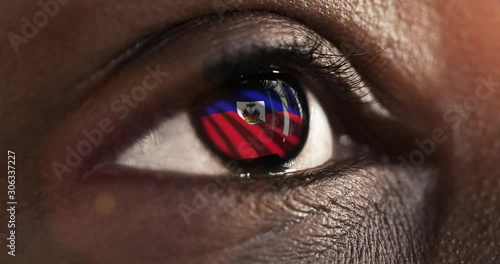 Woman black eye in close up with the flag of haiti in iris with wind motion. video concept photo
