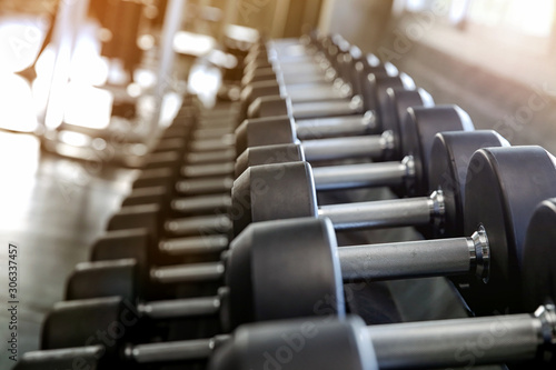 Motivation for Sport. Dumbbell sets in the gym. Sports equipment on a gymnasium background. Side view.  Selective focus.