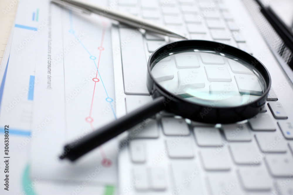 Magnifying glass lies on white keyboard on Magnifying glass lies on white keyboard on