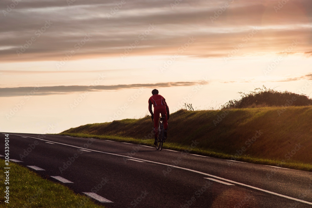 cyclist climbing a slope at sunset
