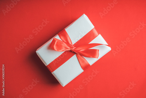 Christmas gift with red ribbon on the red background. Christmas and New Year background.