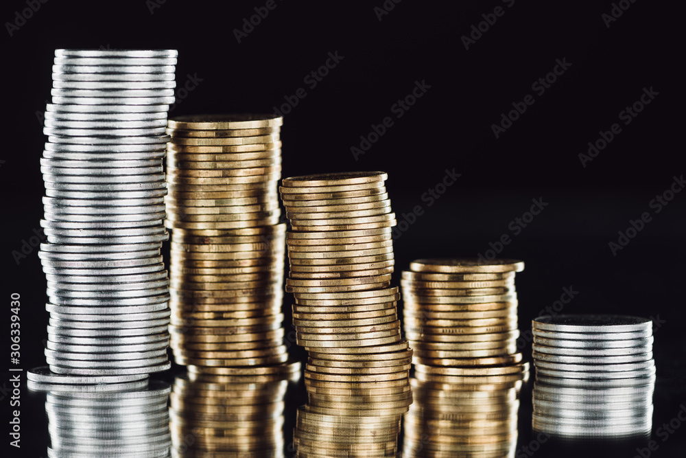 stacks of silver and golden coins on surface with reflection isolated on black stacks of silver and golden coins on surface with reflection isolated on black