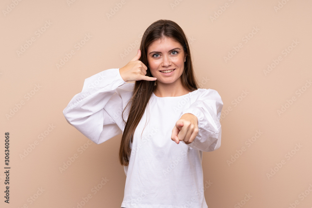 Young girl over isolated background making phone gesture and pointing front Young girl over isolated background making phone gesture and pointing front