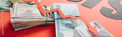 panoramic shot of recession arrow on euro, dollar and ruble banknotes on red background with lighting