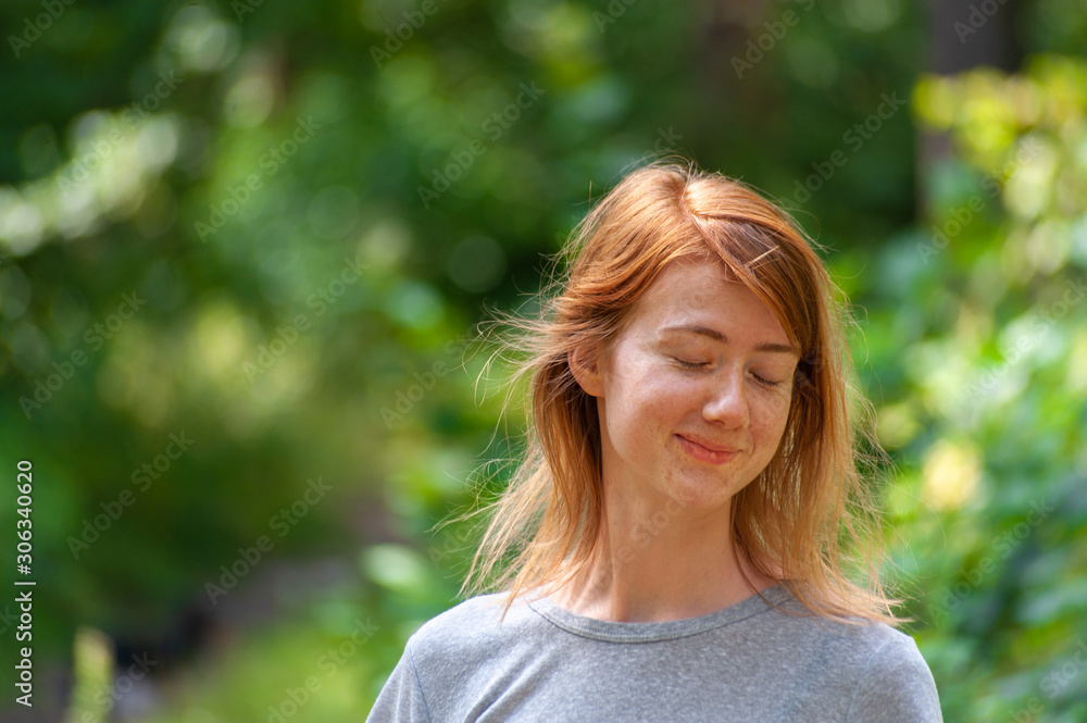 Shy redhead young naturally beautiful girl stays in simple summer outfit outdoor