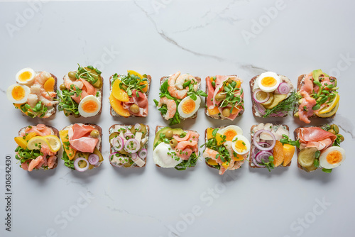top view of delicious danish smorrebrod sandwiches on white marble surface