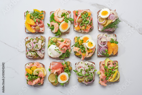 top view of traditional danish smorrebrod sandwiches on white marble surface
