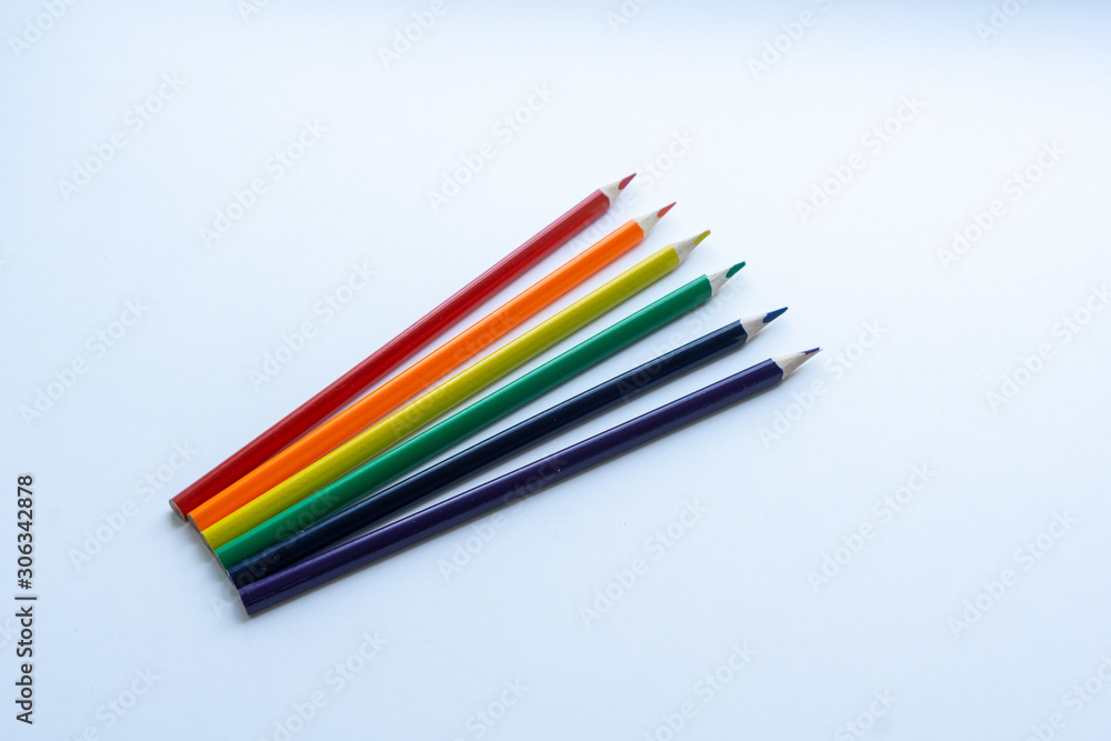 Set of six sharp rainbow-colored pencils except blue, from top view on a white background. Concept of creativity. Art supplies. Minimalism. Childhood. LGBT. Set of six sharp rainbow-colored pencils except blue, from top view on a white background. Concept of creativity. Art supplies. Minimalism. Childhood. LGBT.
