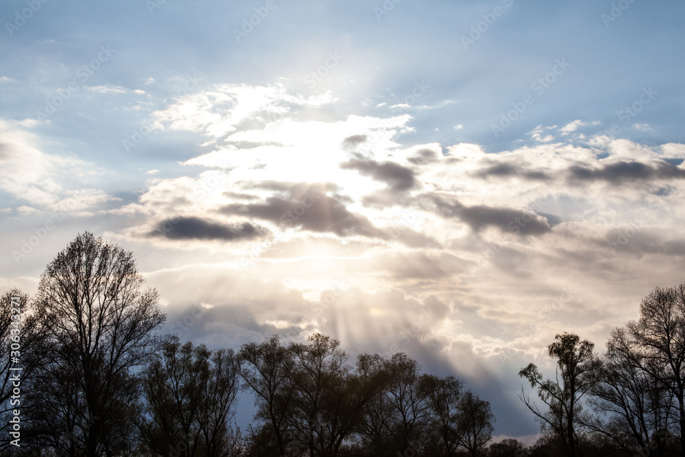 Sun rays from behind the clouds over the trees Sun rays from behind the clouds over the trees