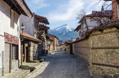 An old street in the mountain town of Bansko, now the largest mountain resort in Bulgaria. In the background the Todorka peak