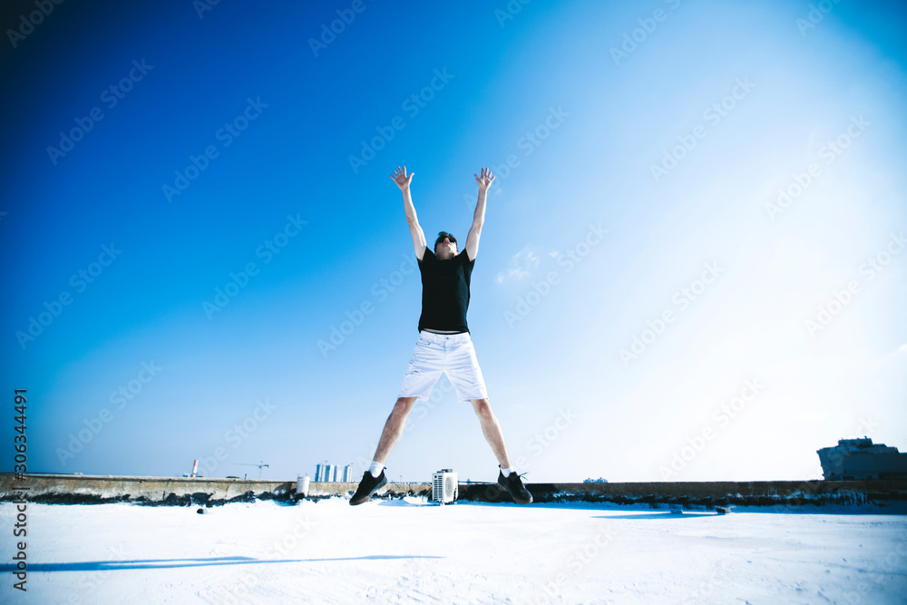 Young attractive man jumping in the air on the roof of a residential building