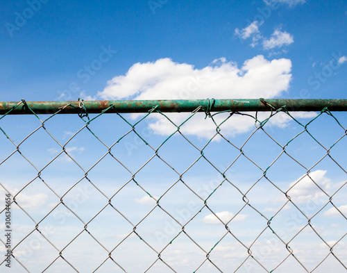 Blue sky behind the metal mesh fence