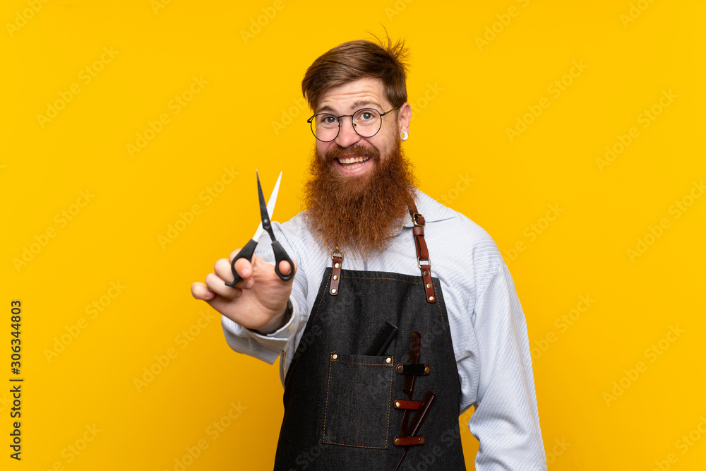 Barber with long beard in an apron over isolated yellow background with happy expression