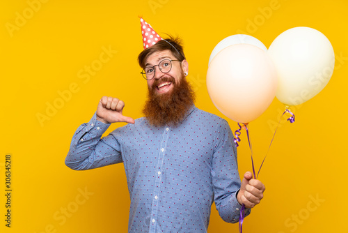 Photography Redhead man with long beard holding balloons over isolated yellow background pro