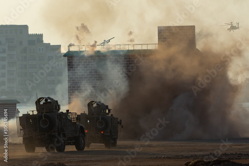 Military chopper and army vehicles flying and driving entering into the smoke and war . Military concept of power, force, strength, air raid, explosion. photo