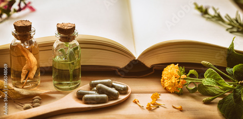Obraz na plátně Traditional medicine with plants and book on the table detail