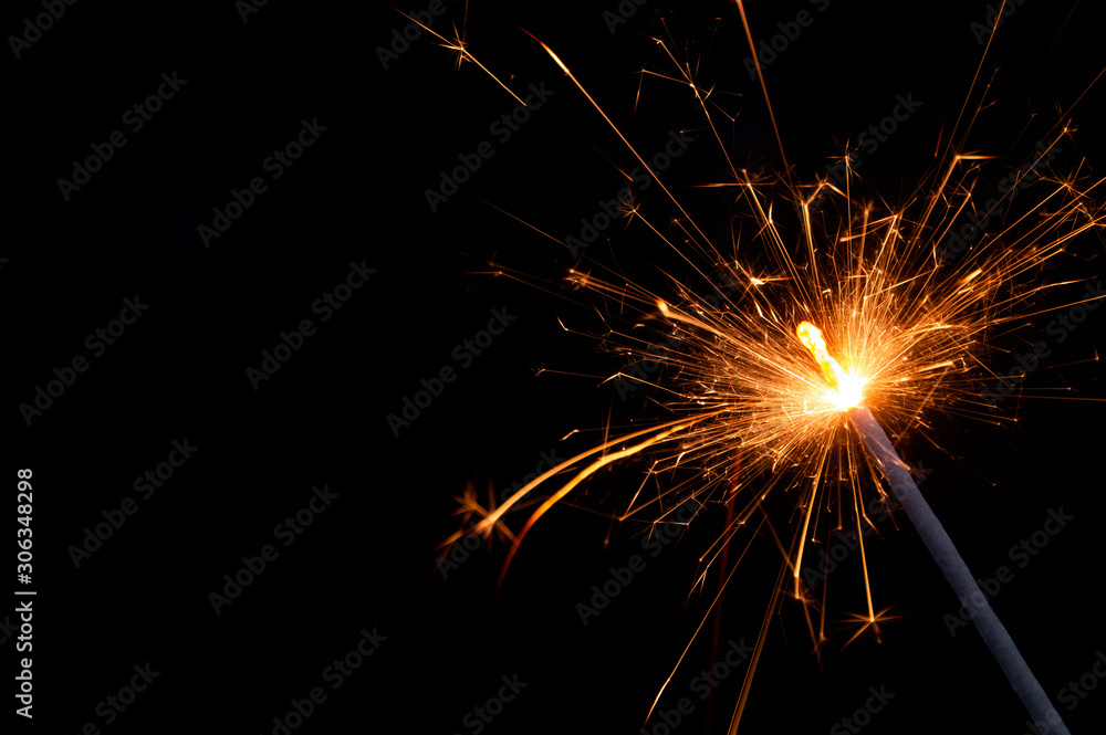 Burning firework sparkler on black background with room for text