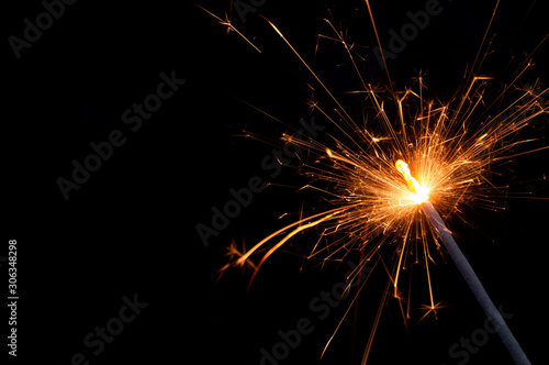 Burning firework sparkler on black background with room for text