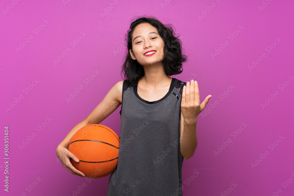 Young Asian woman playing basketball over isolated purple background Young Asian woman playing basketball over isolated purple background