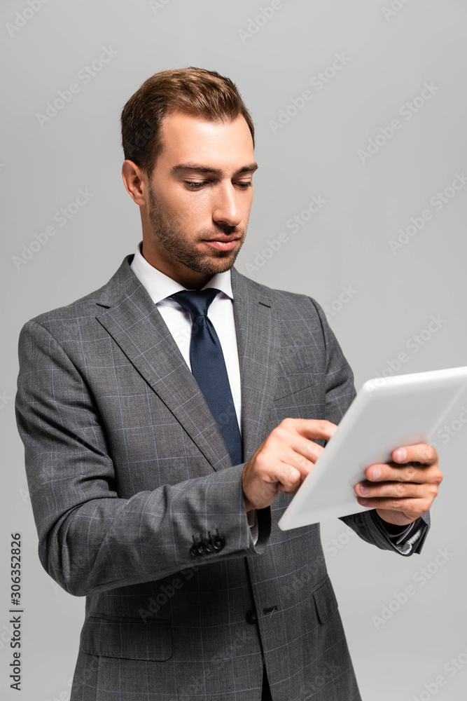 handsome businessman in suit using digital tablet isolated on grey handsome businessman in suit using digital tablet isolated on grey