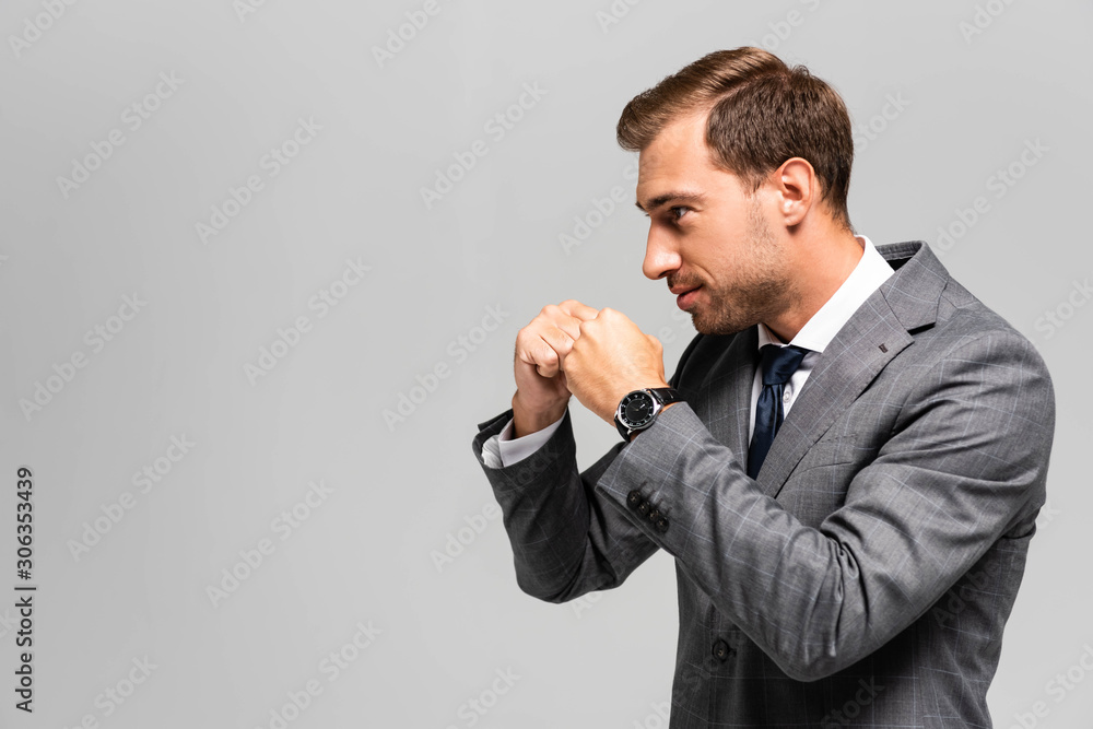 side view of handsome businessman in suit punching isolated on grey side view of handsome businessman in suit punching isolated on grey