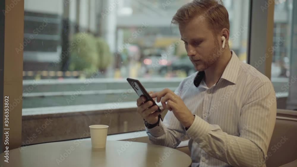 Businessman checking smartphone by the window Businessman checking smartphone by the window