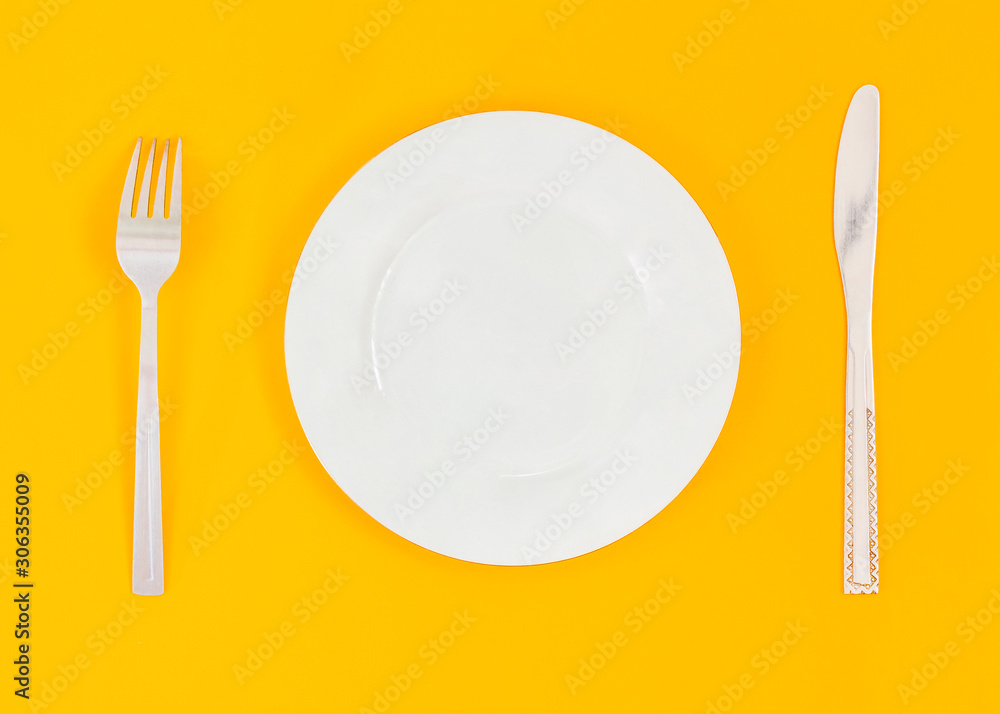 Empty plate, fork, knife on yellow background. Top view Empty plate, fork, knife on yellow background. Top view