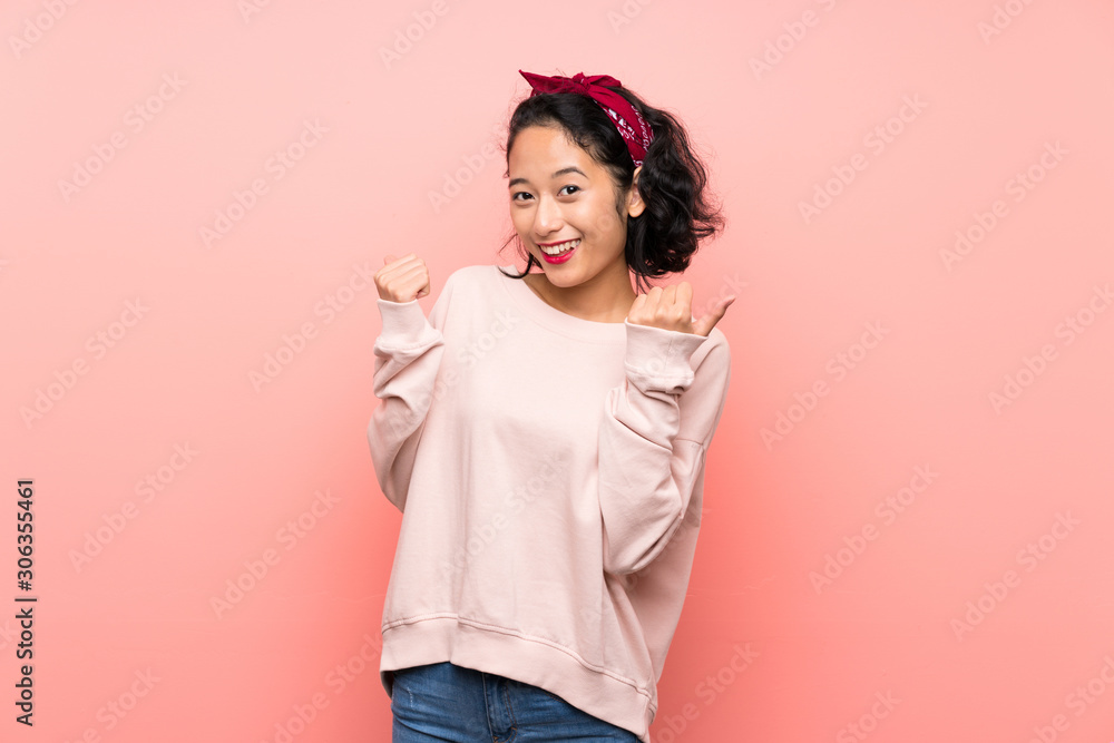 Asian young woman over isolated pink background with thumbs up gesture and smiling Asian young woman over isolated pink background with thumbs up gesture and smiling