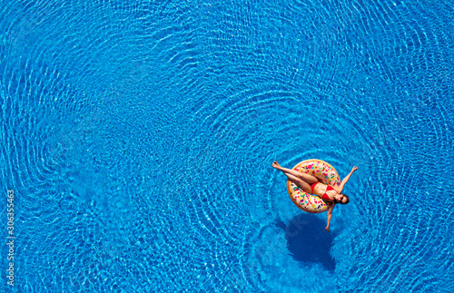 Aerial view of a woman in red bikini lying on a donut in the pool